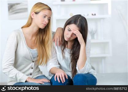 friend comforting sorrowful young female teenager