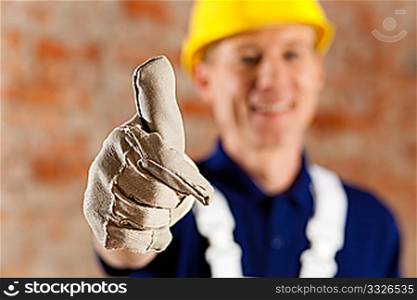 Friendly and reliable construction worker giving thumbs up, focus on thumb