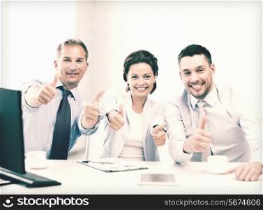 friendly business team showing thumbs up in office