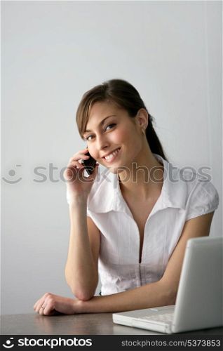 Friendly businesswoman with mobile phone and laptop