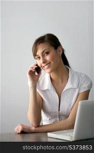 Friendly businesswoman with mobile phone and laptop