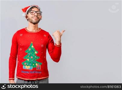 Friendly Christmas man pointing to a space to the side. Friendly smiling young man in christmas clothes pointing at a promo. Cheerful christmas man concept pointing promo offer isolated