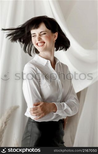 Friendly confident young woman with folded arms smiling at the camera and having fun. Girl in white shirt and leather skirt sitting at home studio.. Friendly confident young woman with folded arms smiling at the camera and having fun. Girl in white shirt and leather skirt sitting at home studio