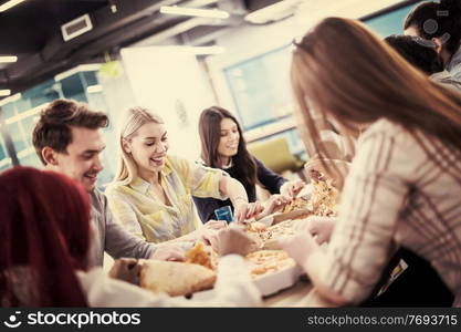 Friendly diverse multiethnic business team eating sharing pizza together in startup office, multiracial coworkers staff group enjoying break talking laughing on lunch time at meeting