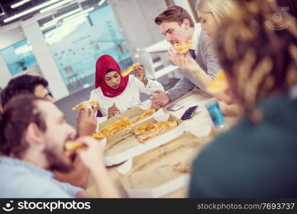 Friendly diverse multiethnic business team eating sharing pizza together in startup office, multiracial coworkers staff group enjoying break talking laughing on lunch time at meeting