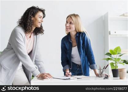 friendly female colleagues discussing work laughing office