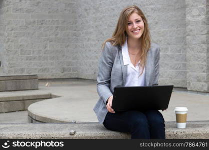 Friendly girl working on laptop outside