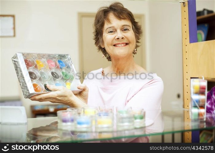 Friendly, happy store clerk holding up a gift set of candles.