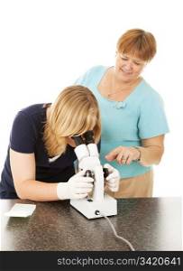 Friendly high school science teacher assists one of her students looking through the microscope. Isolated on white.