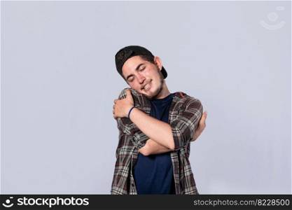 Friendly man hugging himself, Pleased young man hugging himself, Attractive positive looking friendly young man with a sincere smile embracing himself gratefully