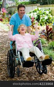Friendly orderly and senior lady having great fun as he pushes her wheelchair.