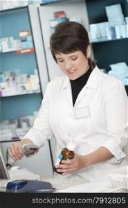 Friendly Pharmacist Working with Barcode Reader in the Drugstore .