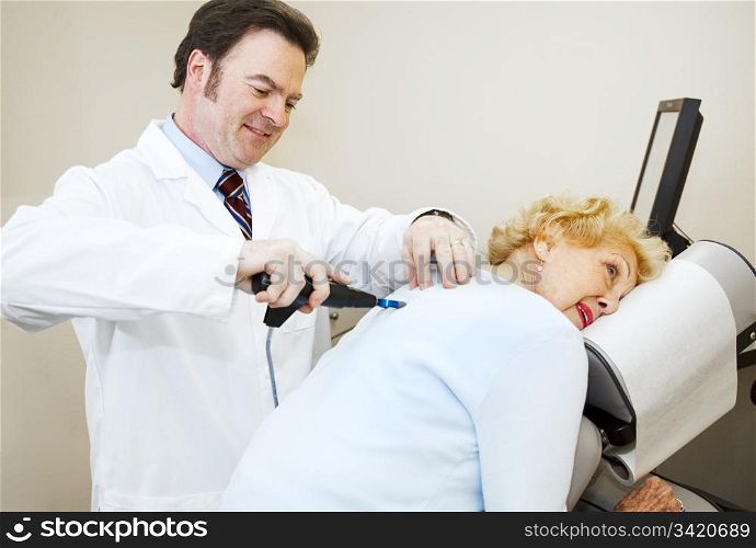 Friendly, smiling chiropractor adjusting a senior woman&rsquo;s back.