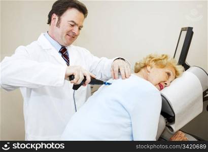Friendly, smiling chiropractor adjusting a senior woman&rsquo;s back.