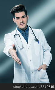 Friendly smiling doctor offering his hand for handshake over gray background