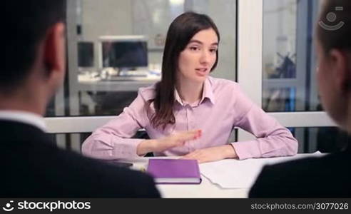 Friendly smiling female financial consultant shaking hands with her clients over the office desk after pleasant talk and efficient negotiation.