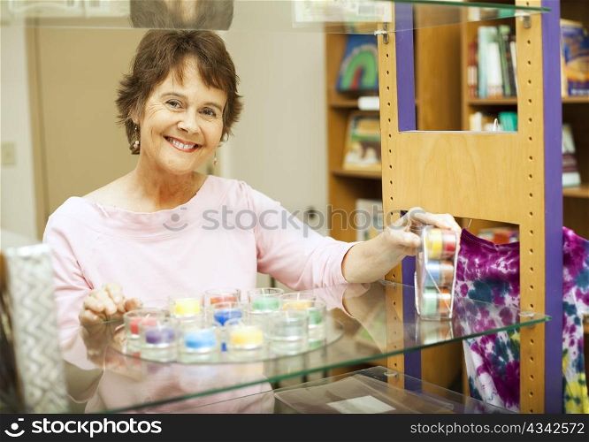 Friendly store clerk smiles as she&rsquo;s setting up a display.
