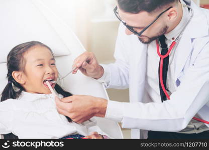 Friendly young dentist examining happy child teeth in dental clinic. Dentistry concept.