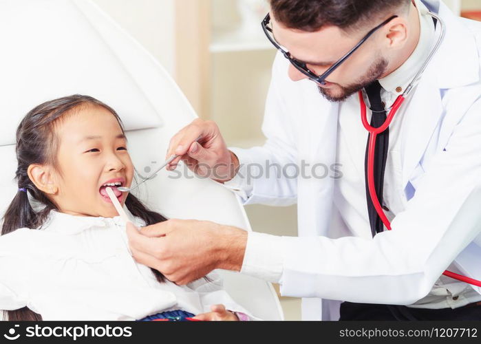 Friendly young dentist examining happy child teeth in dental clinic. Dentistry concept.. Dentist examining child teeth in dental clinic.