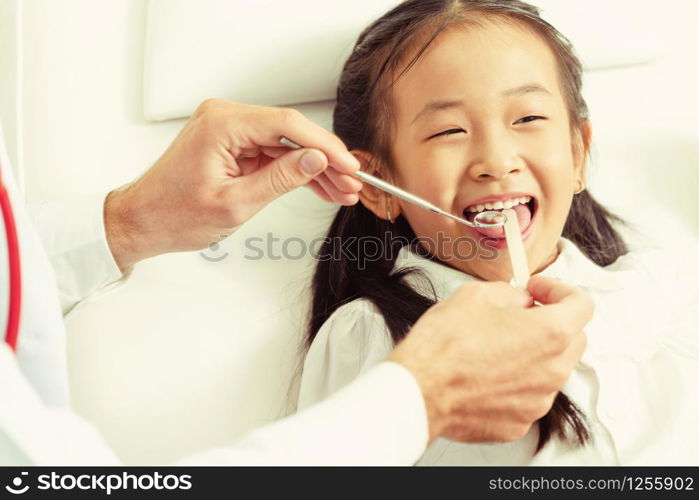 Friendly young dentist examining happy child teeth in dental clinic. Dentistry concept.