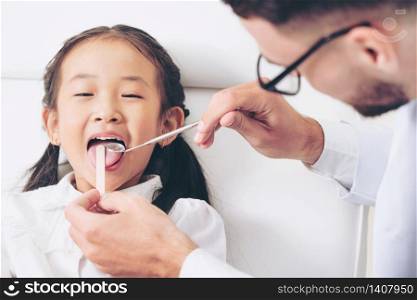 Friendly young dentist examining happy child teeth in dental clinic. Dentistry concept.. Dentist examining child teeth in dental clinic.