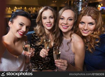 friends, bachelorette party, technology and holidays concept - happy smiling young pretty women with champagne glasses taking selfie at night club
