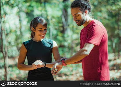 Friends checking progress on their smart watches after outdoor training. Friends Looking at Their Smart Watches After Outdoor Training