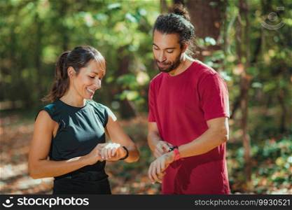 Friends checking progress on their smart watches after outdoor training. Friends Looking at Their Smart Watches After Outdoor Training