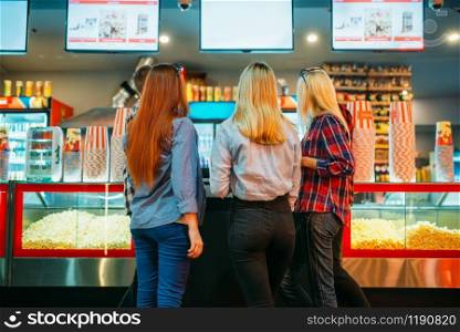 Friends choosing food in cinema bar before the screening, back view. Male and female youth in movie theater. Friends choosing food in cinema bar