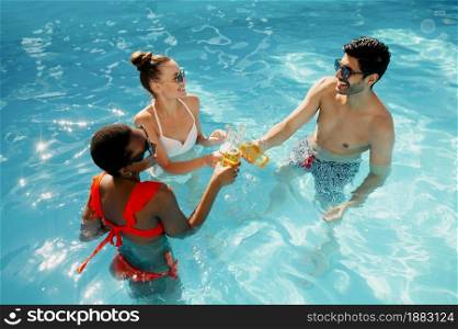Friends drink beverages in the pool, top view. Happy people having fun on summer vacations, holiday party at the poolside outdoors. Friends drink beverages in the pool, top view