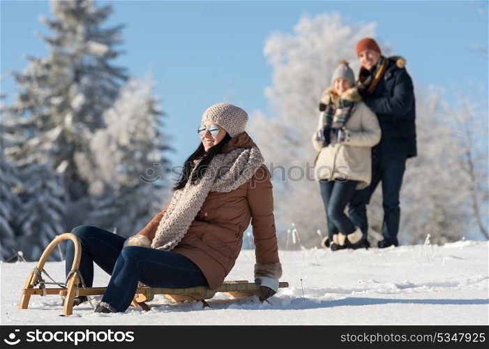 Friends enjoy sunny winter day on wooden sledge