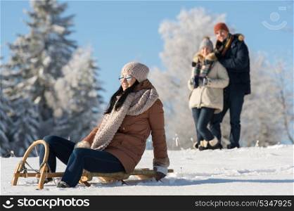 Friends enjoy sunny winter day on wooden sledge