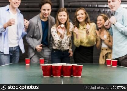 friends enjoying beer pong game table bar