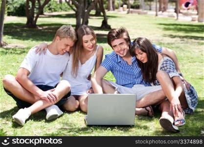 Friends enjoying movie in park on laptop and having great time on sunny day