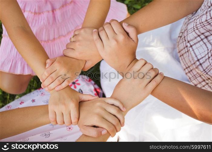 Friends forever - three girls hold hands together, close up arms