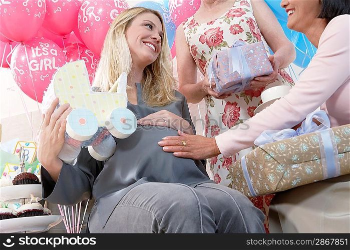 Friends giving gifts to woman at baby shower