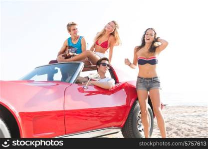 friends group at beach in sports car convertible having fun party with guitar