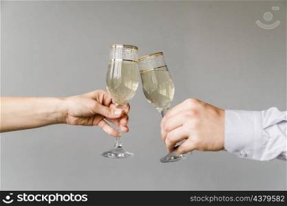 friends hands clinking glasses champagne grey background
