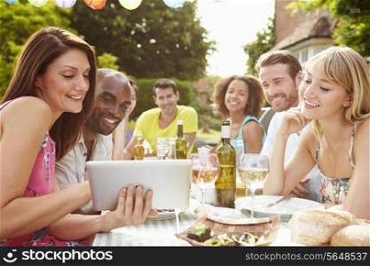 Friends Having Barbeque At Home Looking At Digital Tablet