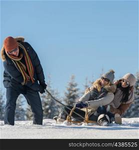 Friends having fun on snow sledge sunny wintertime