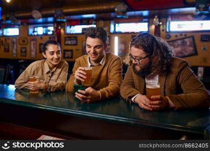 Friends having fun sitting at bar counter in pub. Young people talking drinking beer and using smartphone. Friends having fun, talking drinking beer and using smartphone