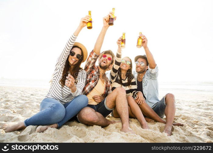 Friends having fun together at the beach and drinking a cold beer