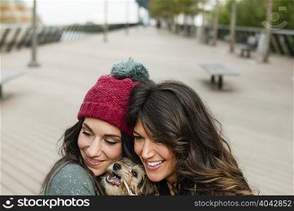 Friends holding pet dog for photograph