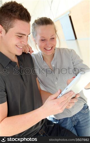 Friends in school corridor using electronic tablet