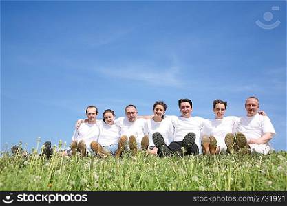 Friends in white T-shorts have a rest on a grass