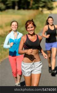 Friends jogging together outdoors sunny path smiling