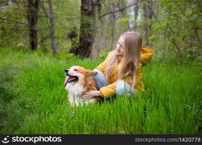 friends - little girl with corgi dog walking outdoors at sunny spring day