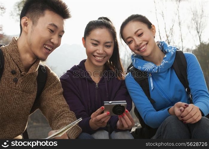 Friends looking at the picture on the screen of digital camera