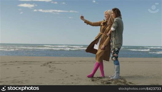 Friends making selfie. two beautiful young women making selfie at autumn day on the beach