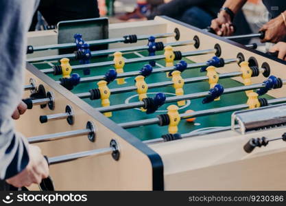 Friends play table football game, spend free time in entertainment center. Recreation and leisure concept. Active players. Sport games